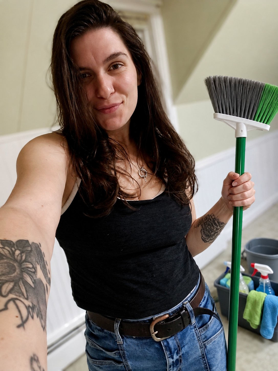 Cassidy holding a broom, with cleaning supplies behind her